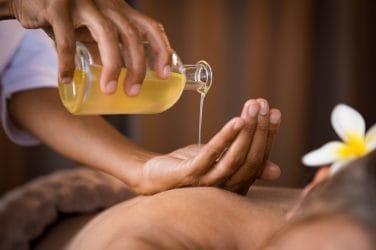 massageolie wordt in een hand geschonken boven een massageklant