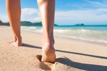 voeten van iemand die over het strand wandelt