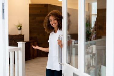 beauty professional doet vriendelijk de deur open voor een klant