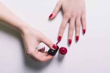 handen van een vrouw die rode nagellak aanbrengt