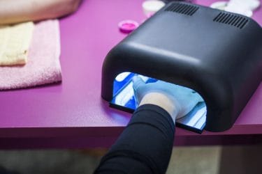 klant houdt nagels met gel in UV-lamp om de gel uit te harden.