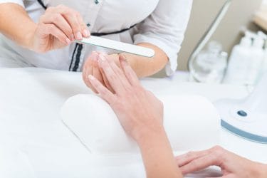 manicure bereidt handen van klant voor op dip powder nails behandeling