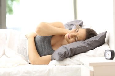 vrouw in bed met fibromyalgie klachten, pijn in nek
