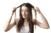 vrouw met handen in het haar vanwege overmatige haaruitval door stress.