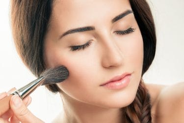 Jonge vrouw brengt make-up aan met kwast