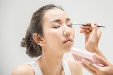 make-up artist brengt make-up aan bij Aziatische vrouw