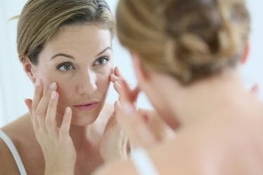 Vrouw van middelbare leeftijd brengt anti-rimpelcrème aan