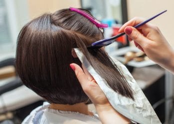 Vrouw met bobkapsel ondergaat een hair colouring behandeling in een kapsalon.